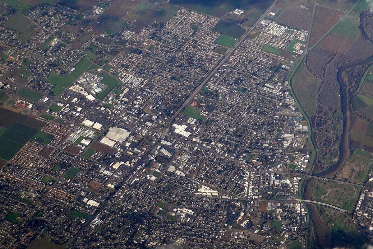Aerial view of Yuba City's street grid, with farm fields around its edges and a river curving along the right side