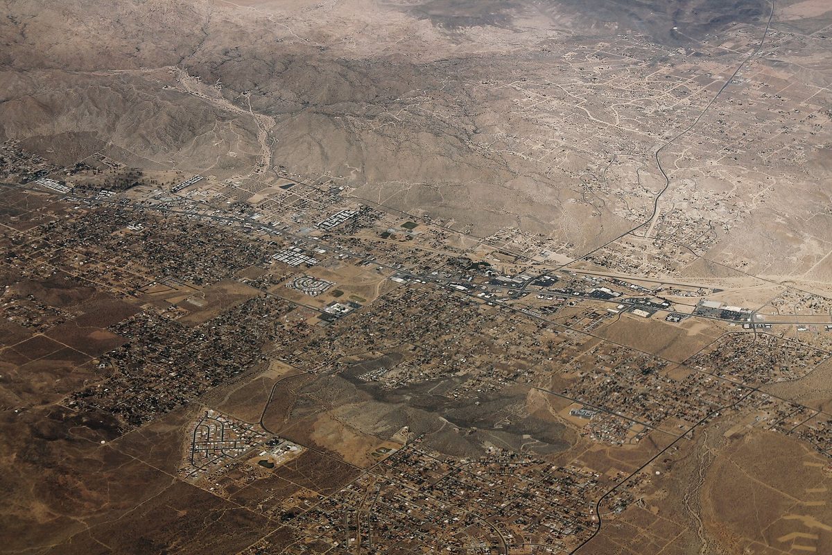 Aerial view of Yucca Valley's grid of streets and houses spread across the desert floor at the foot of bare brown hills